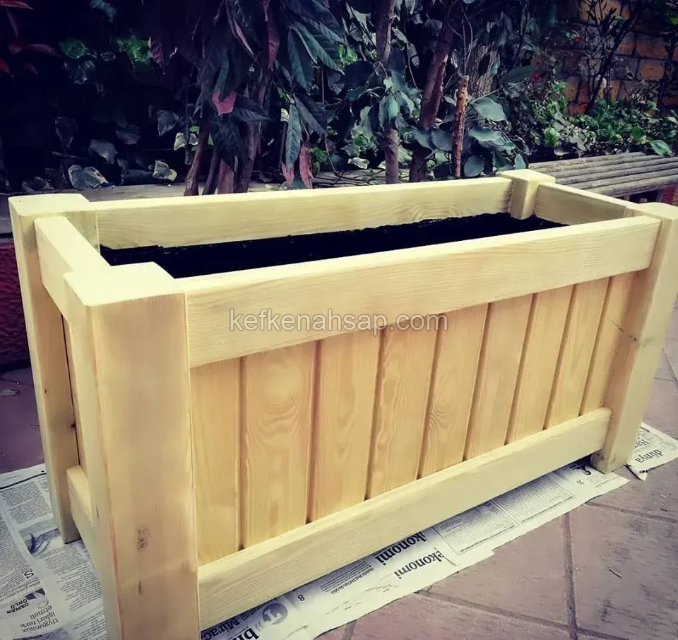 Large light timber planter with a black liner standing on newspaper-covered ground