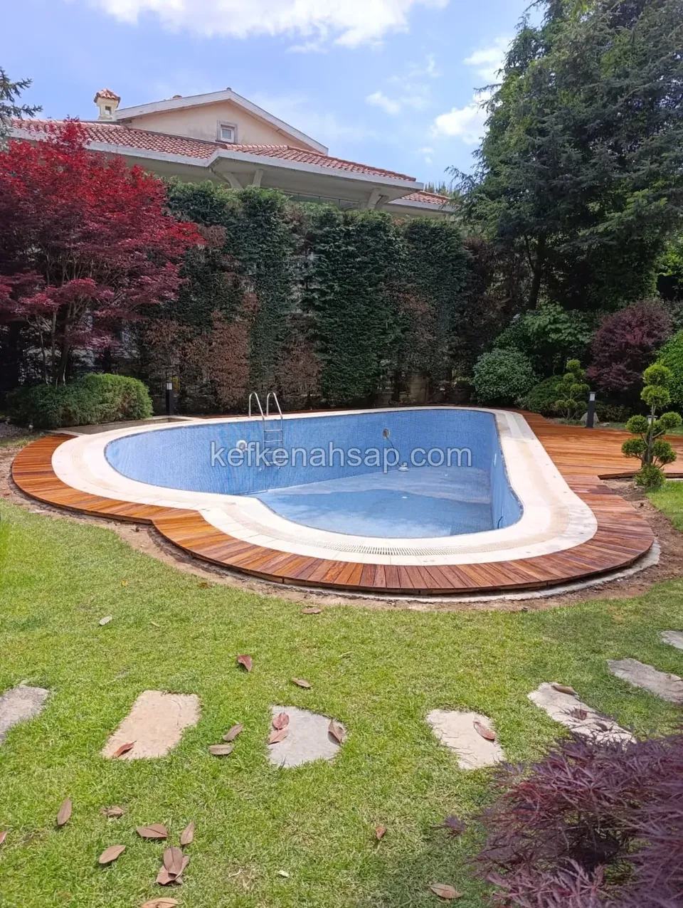 Curved wooden decking border and sunbathing platform installed around an outdoor swimming pool.
