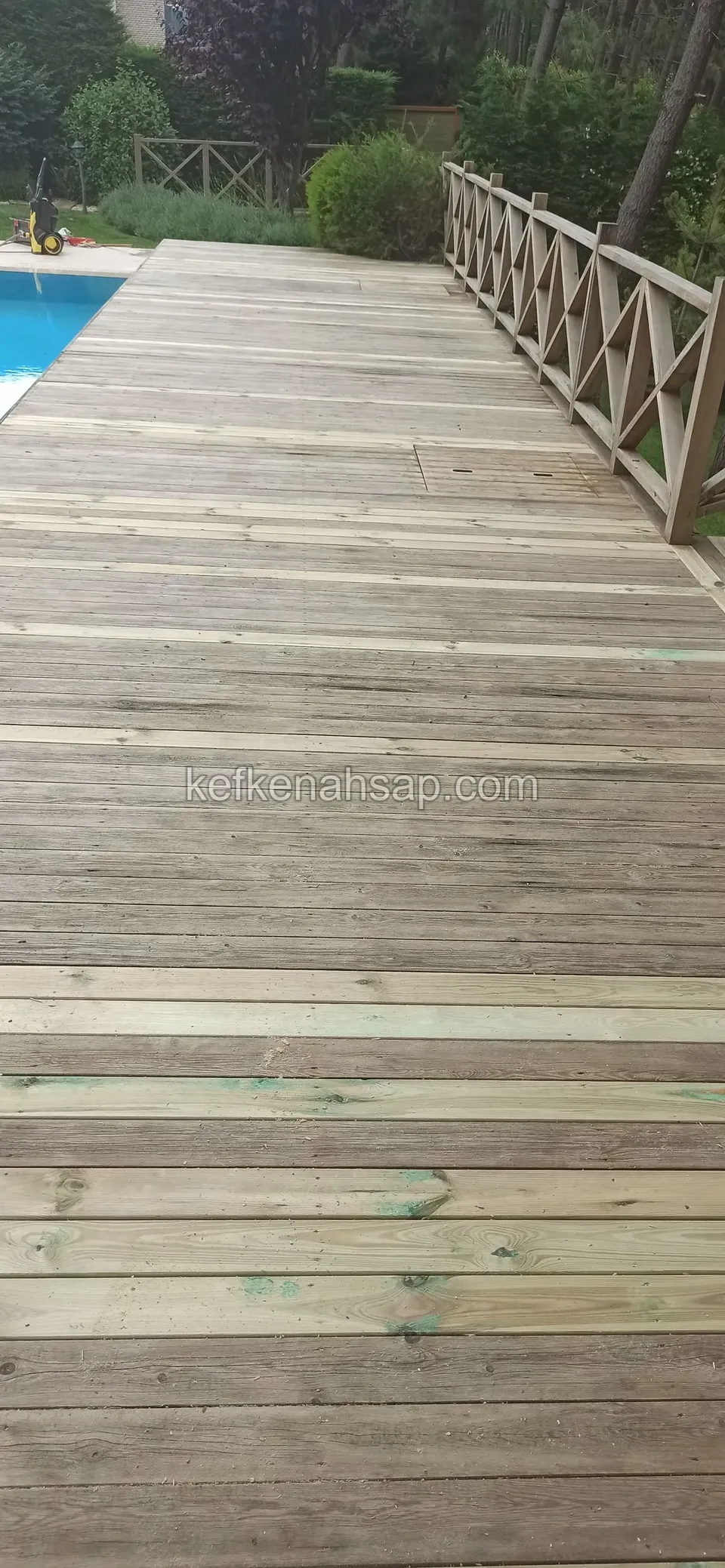 Deck am Pool mit Kreuzgeländer, in dem neue helle Dielen zwischen den alten grauen liegen