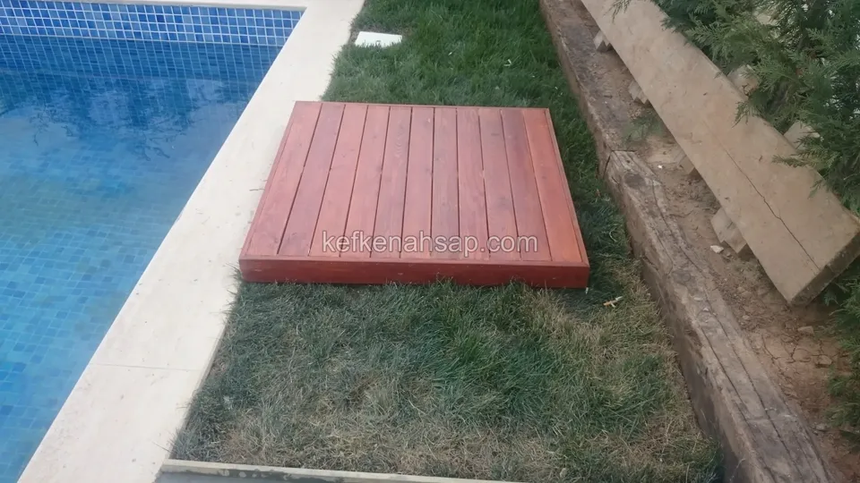 Small reddish timber deck platform placed on the lawn beside a pool