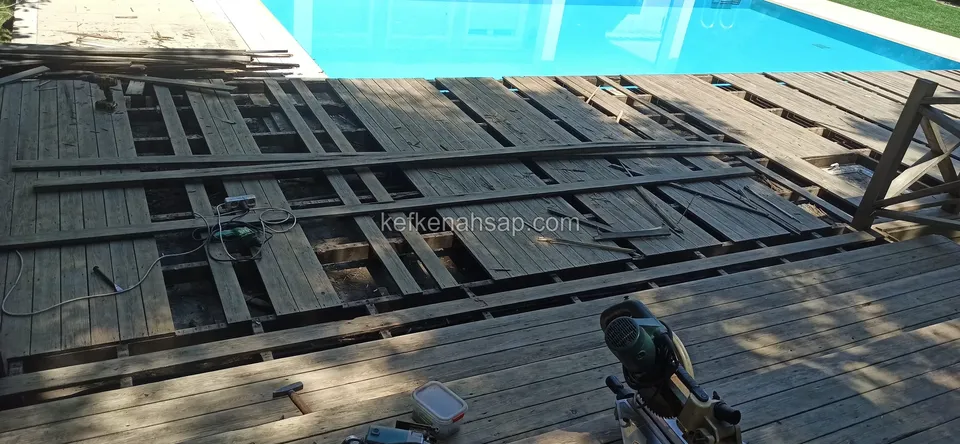 Old deck boards being lifted at the pool edge, with a mitre saw and tools in front