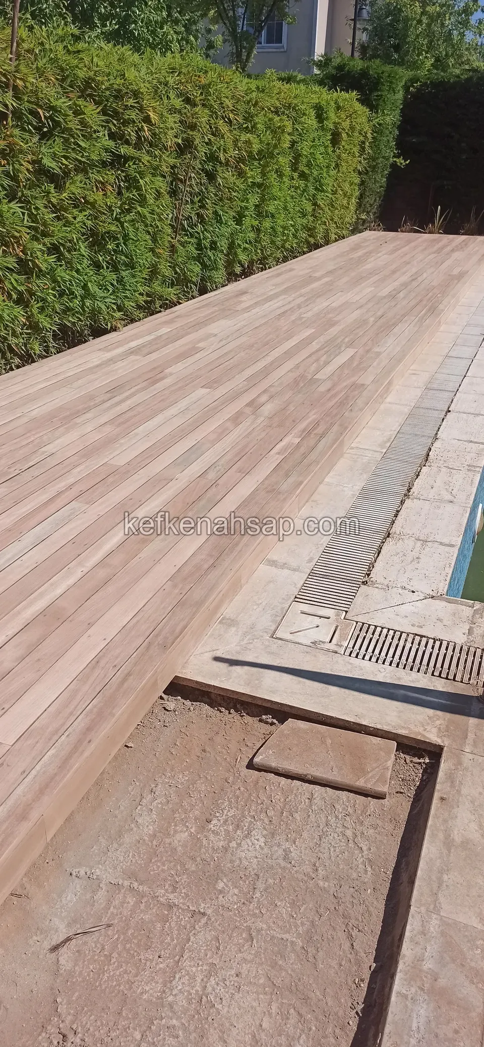 Havuz kenarında pembemsi deck, yanında ızgara ve henüz kaplanmamış bir alan