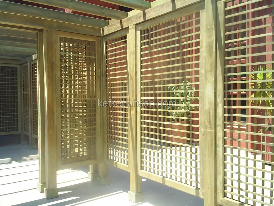 Parlak zeminli teras üzerinde kare gözlü kafes panellerle ayrılmış ahşap kabinler ve çıtalı tavan, yanda bir bitki