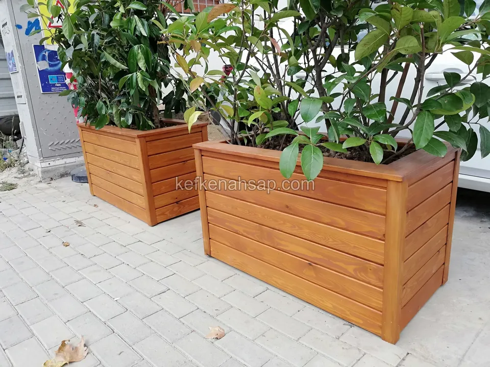 Parke taşı kaldırımda, içlerinde yeşil çalılar olan iki bal rengi ahşap çiçeklik