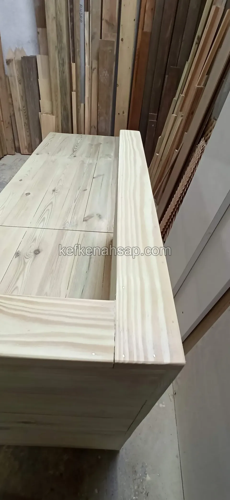 Aus der Nähe die Brettoberseite einer Holzbank mit Deckel, mit Randrahmen und der Fuge des Deckels