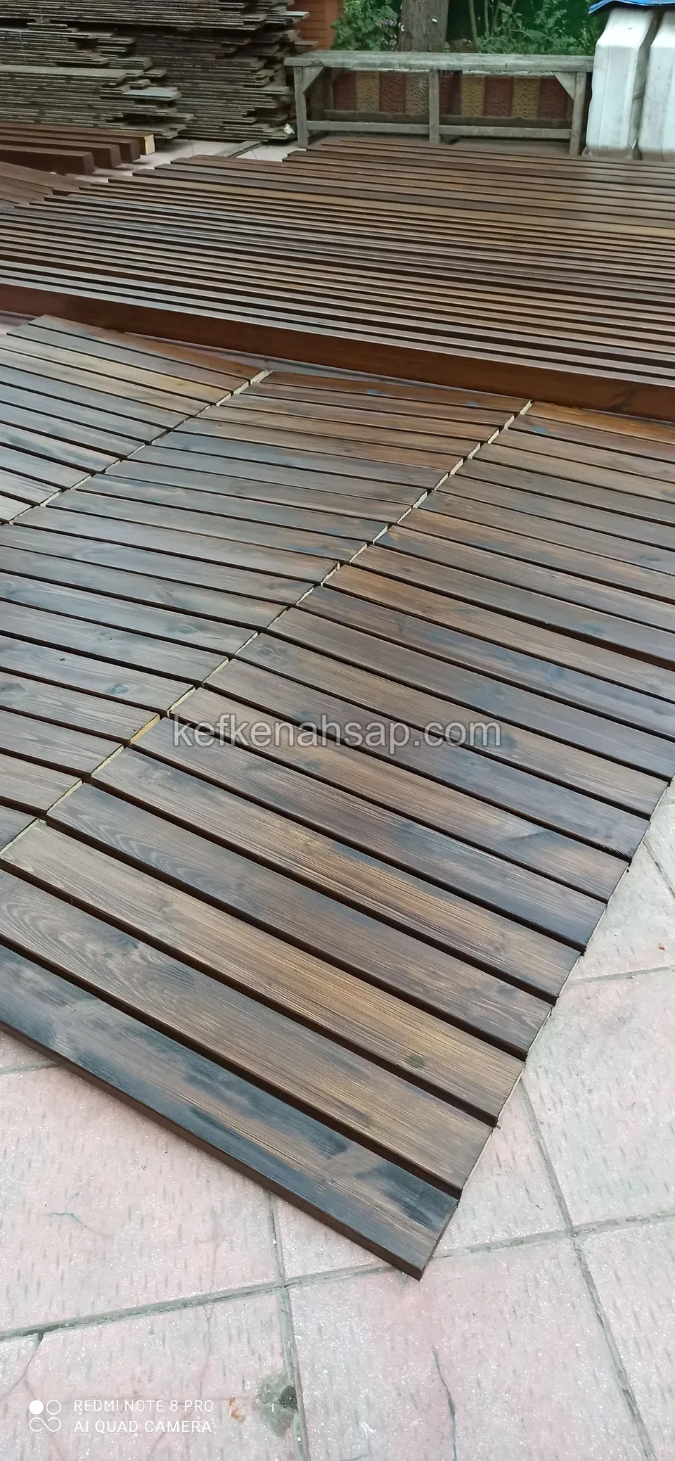 Deck panels made of dark-stained slats laid out on a tiled floor