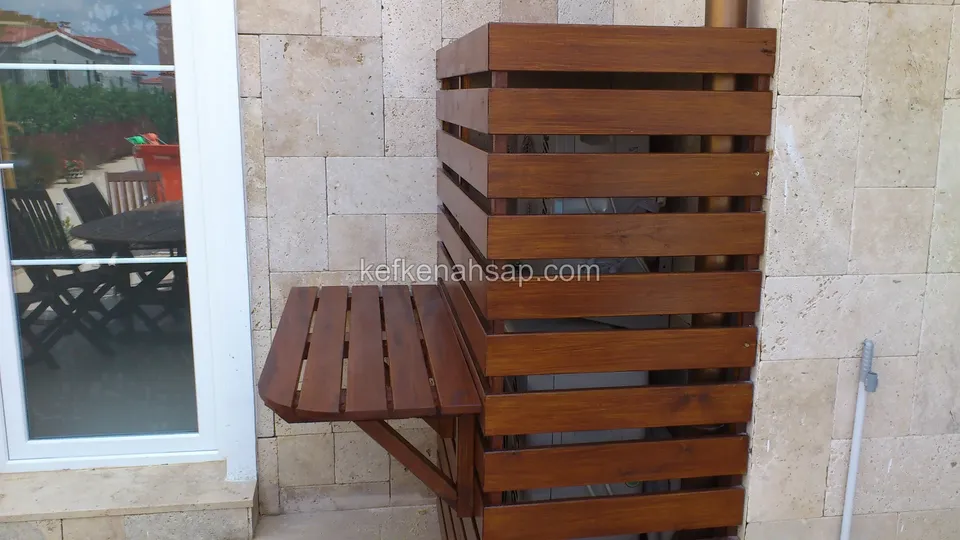 Taş kaplı duvara monte, yatay çıtalı koyu ahşap kapama ve yanına bağlı katlanır ahşap masa