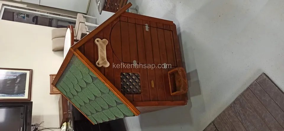 بيت كلب بزخرفة على شكل عظمة وفتحة تهوية صغيرة بشبك في الواجهة، يُرى من الأعلى داخل غرفة