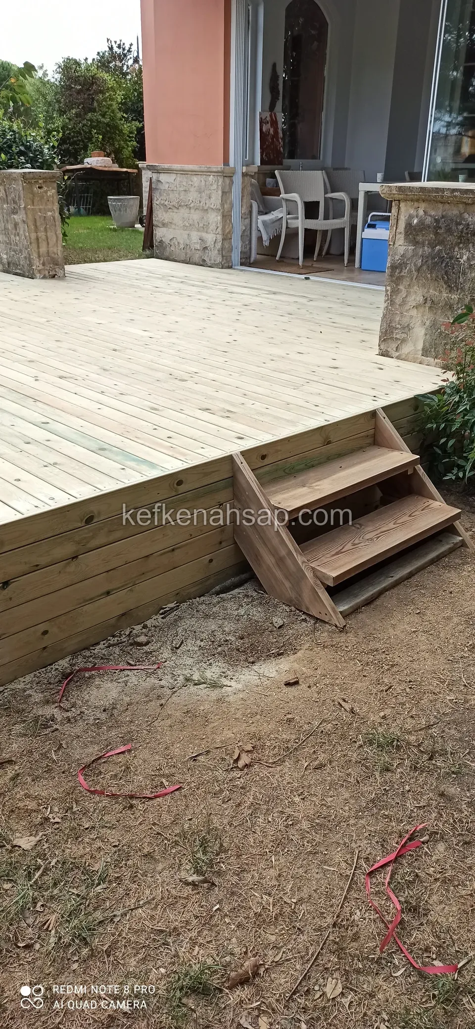 Kenarında ahşap basamak olan açık renkli yükseltilmiş deck, toprak üzerinde kırmızı kablolar