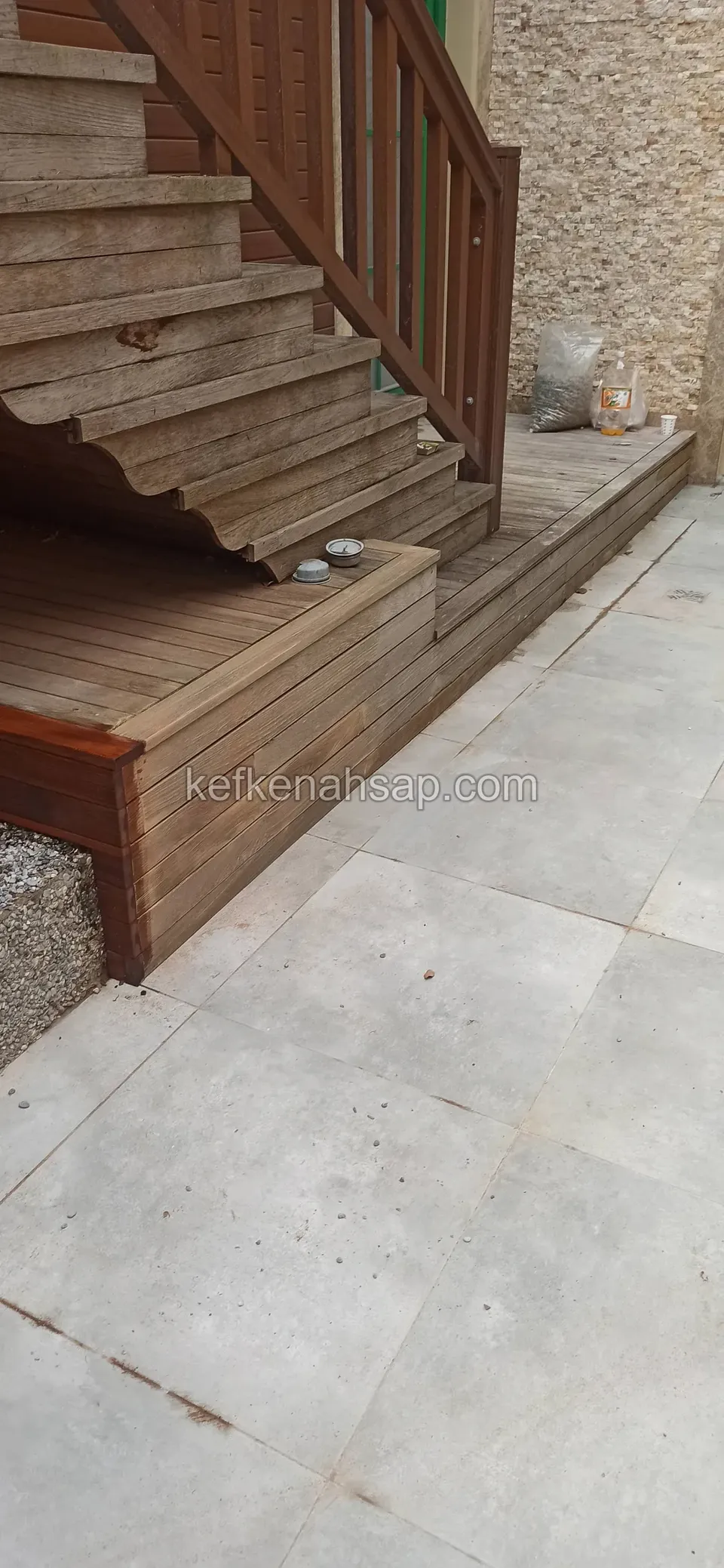 Seramik zemin yanında kırmızımsı kahverengi ahşap merdiven, korkuluğu ve alçak platform