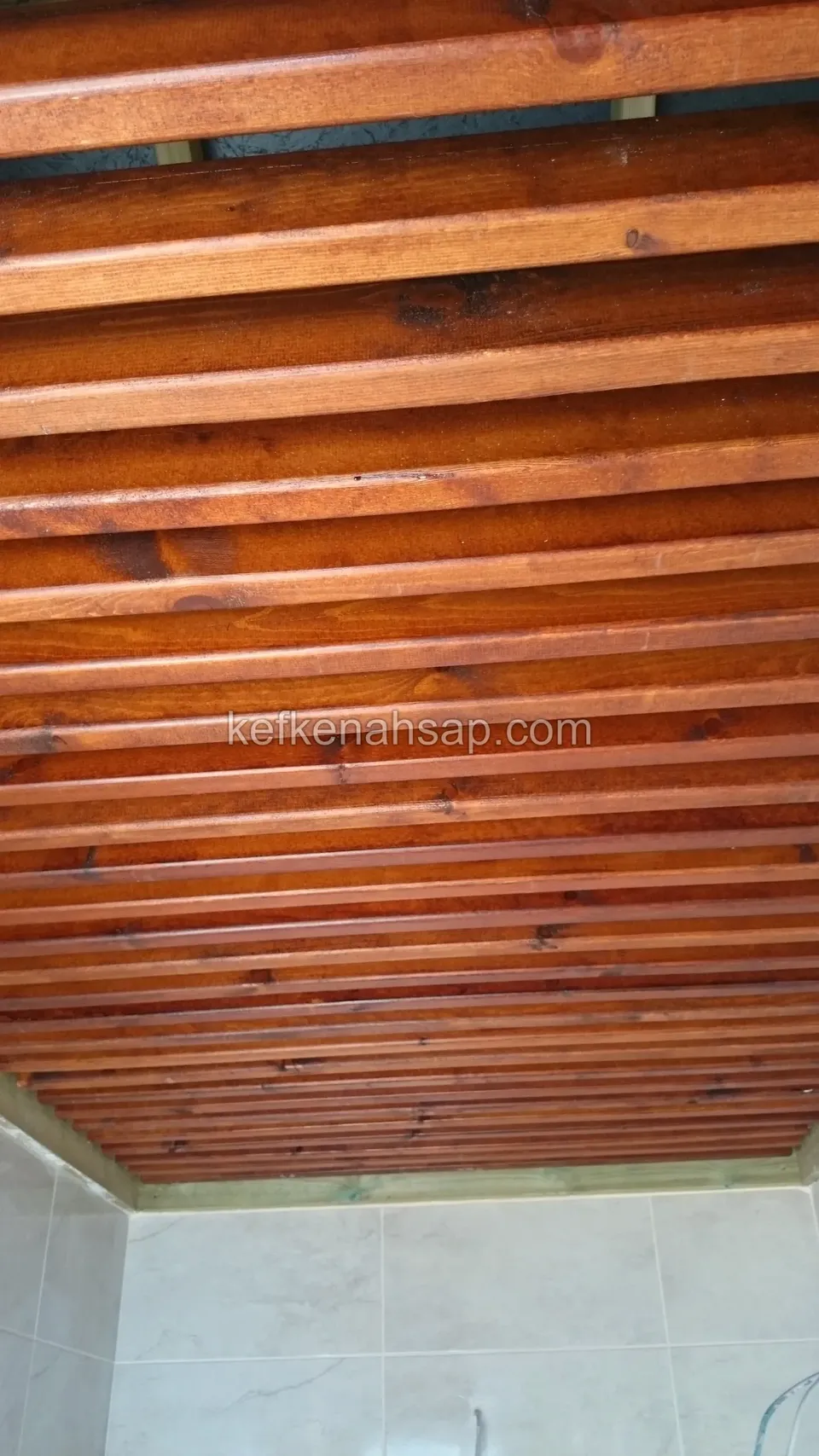 Balkon üstünde kırmızımsı vernikli, sık sıralı ahşap çıtalarla kaplanmış tavan