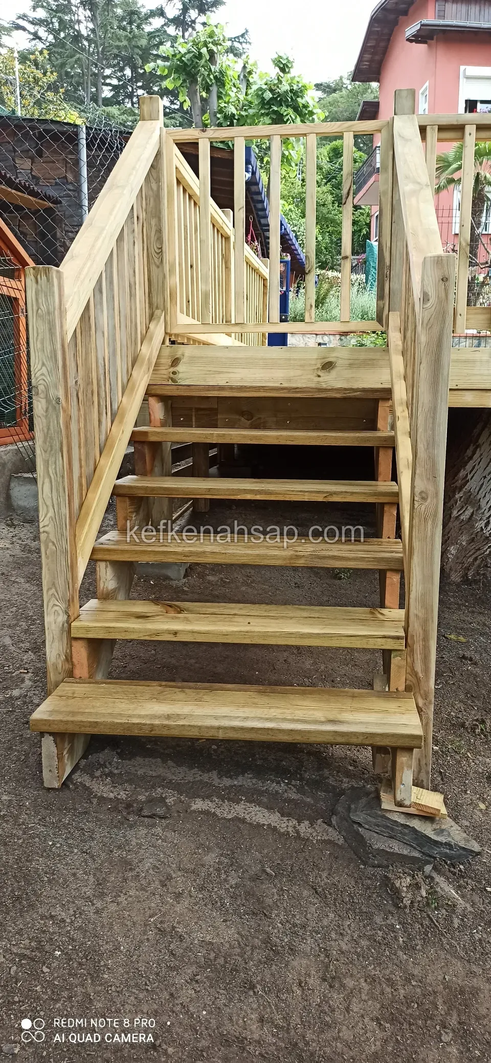 Holztreppe mit Geländer auf beiden Seiten vom Garten zu einer erhöhten Holzplattform