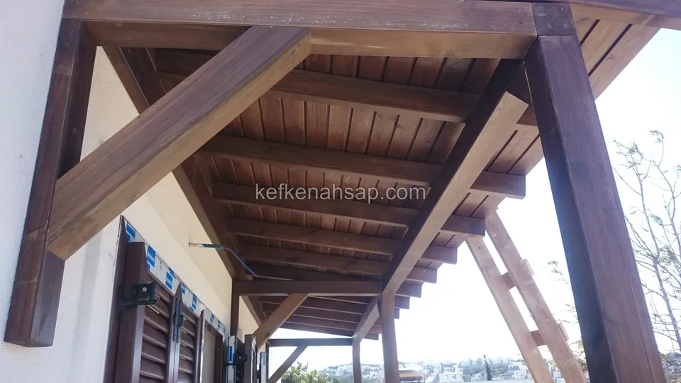 Köşebentli koyu vernikli ahşap saçağın lambri kaplı alt yüzü; altında panjurlu pencereler