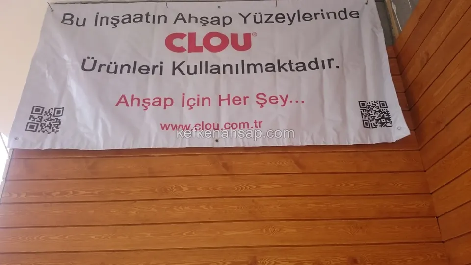 Bina köşesinde yatay döşenmiş lambri cephe kaplaması; üstte asılı bir afiş var