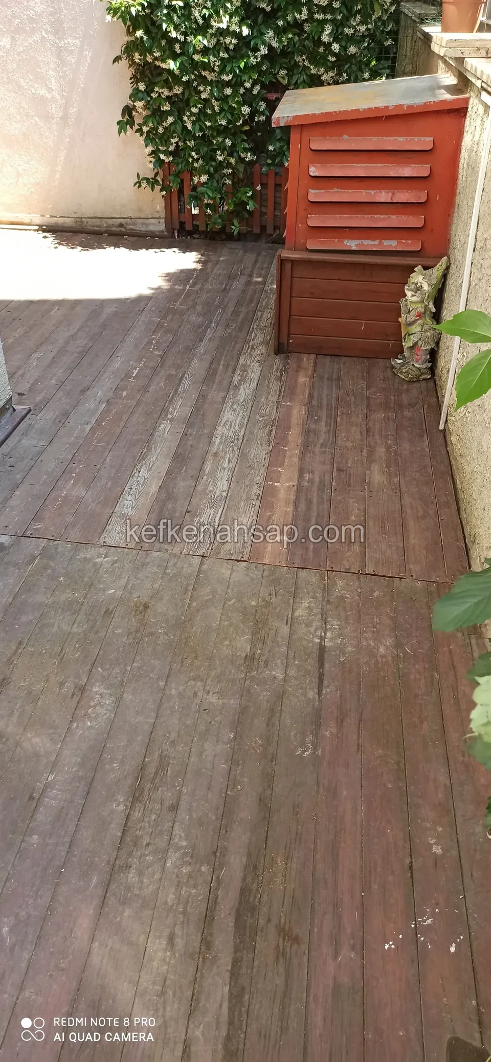 Eskimiş koyu kahverengi deck zemini, köşede kırmızı ahşap kutu ve sandık