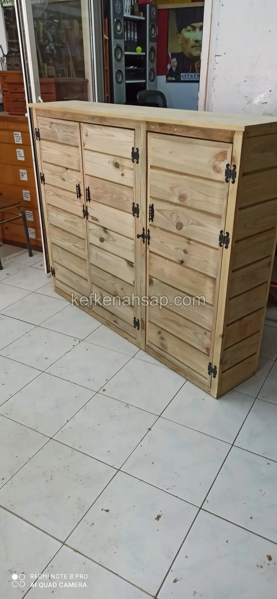 Beyaz fayans zeminde, sıra sıra küçük kapaklı bölmeleri olan açık renk ahşap dolap