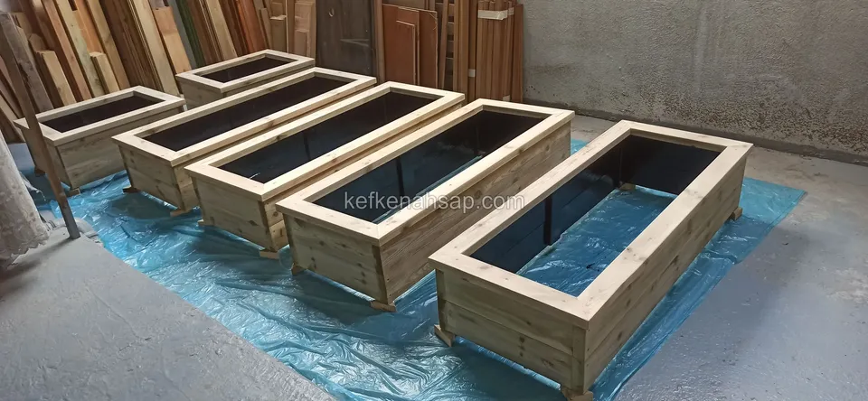Long light timber planters standing in a diagonal row on blue plastic