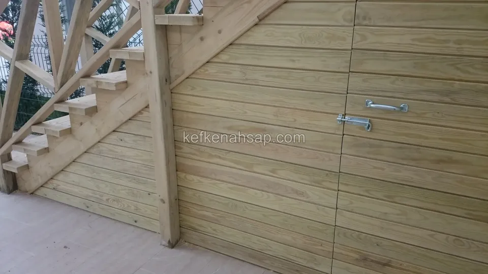 Ahşap dış merdivenin altını kapatan yatay tahta kaplama ve sürgülü, metal kollu depo kapağı