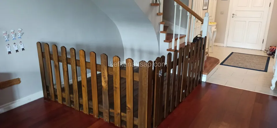 Dunkel lackierte Lattenschranke, die in einem Innenraum mit Parkett vor der Treppe eine Ecke bildet