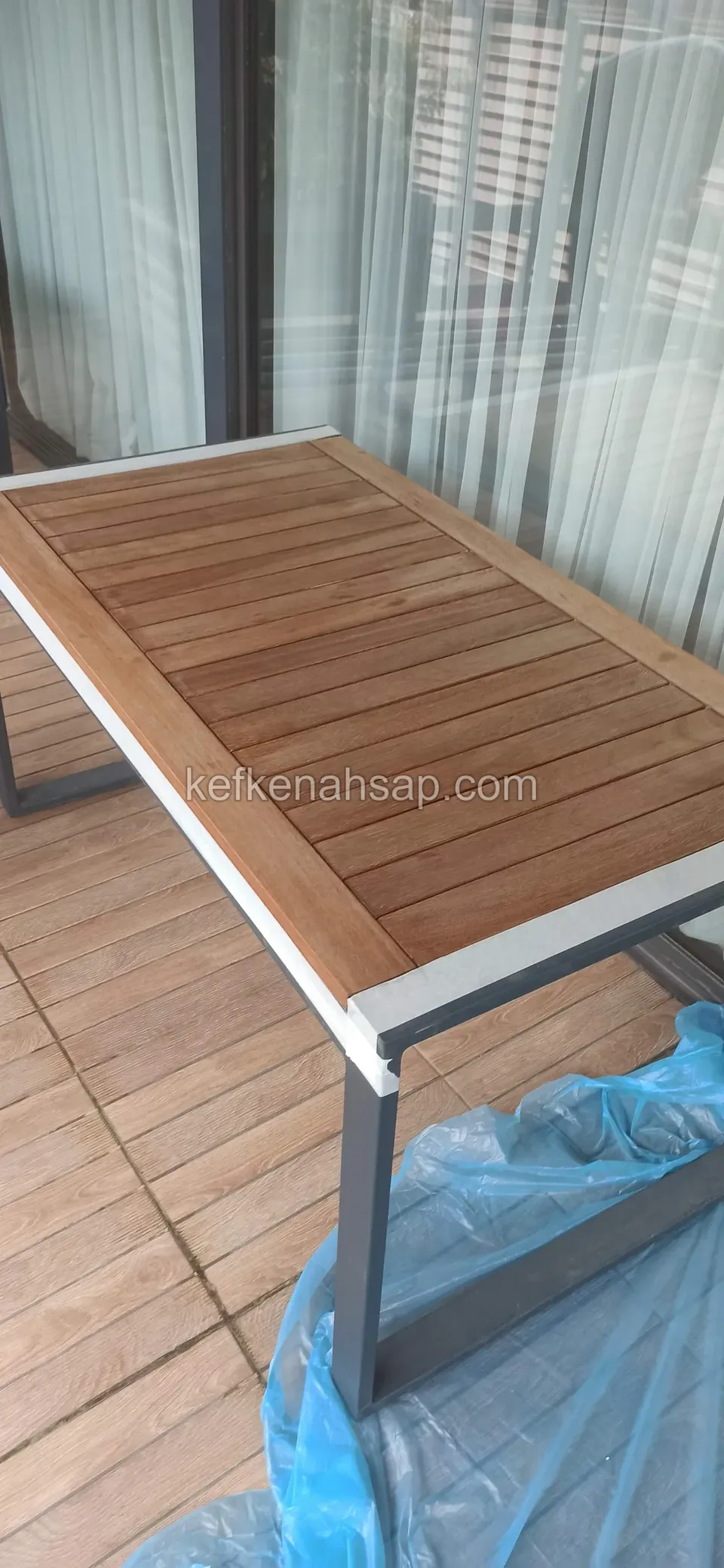 Table with a slatted timber top and grey metal frame on a decked balcony