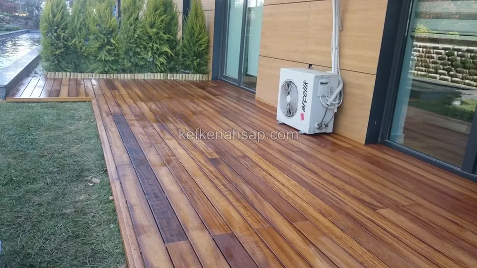 Honey-coloured deck running along the glass doors of a modern timber-clad house