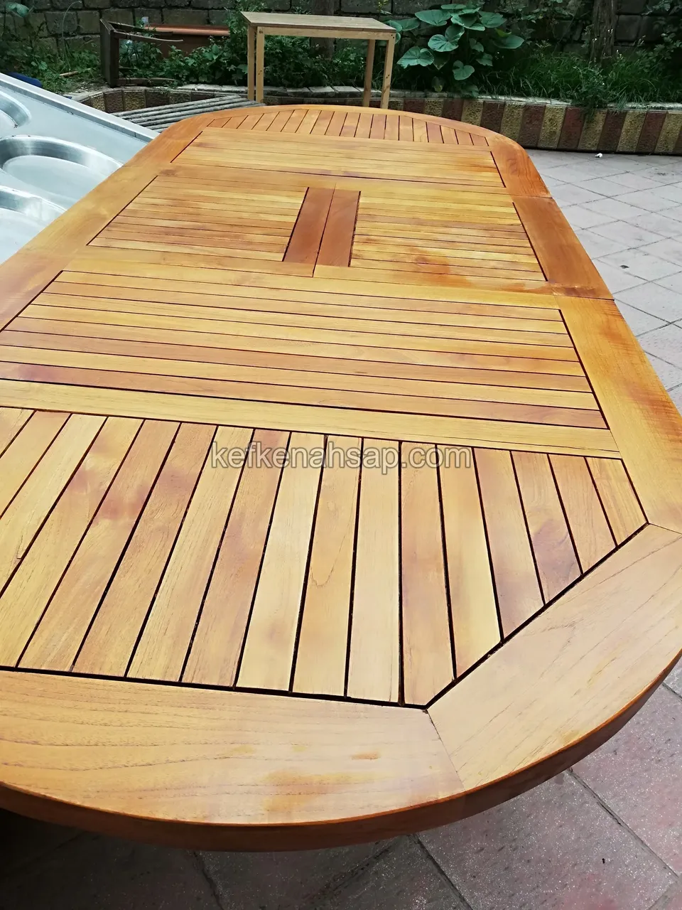 Nahaufnahme einer ovalen Holztischplatte mit Längslatten in der Mitte