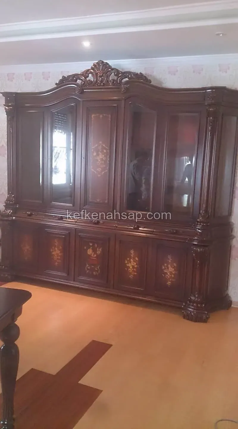 بوفيه كلاسيكي داكن اللمعان بتاج منحوت، في قسمه العلوي أبواب زجاجية وفي أبواب الخزانة السفلية تطعيم بزخارف الزهور