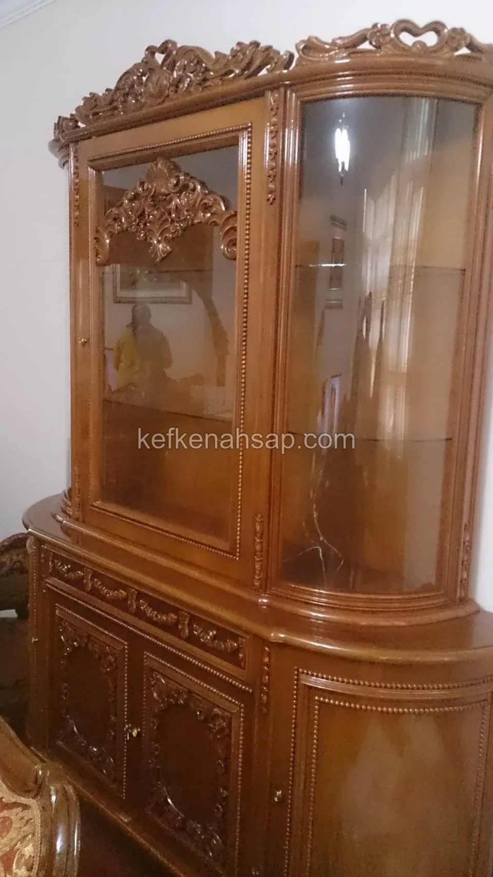 Üstü oymalı, camlı bölmeleri ve kavisli yan camı olan, parlak cilalı klasik ahşap vitrin dolabı