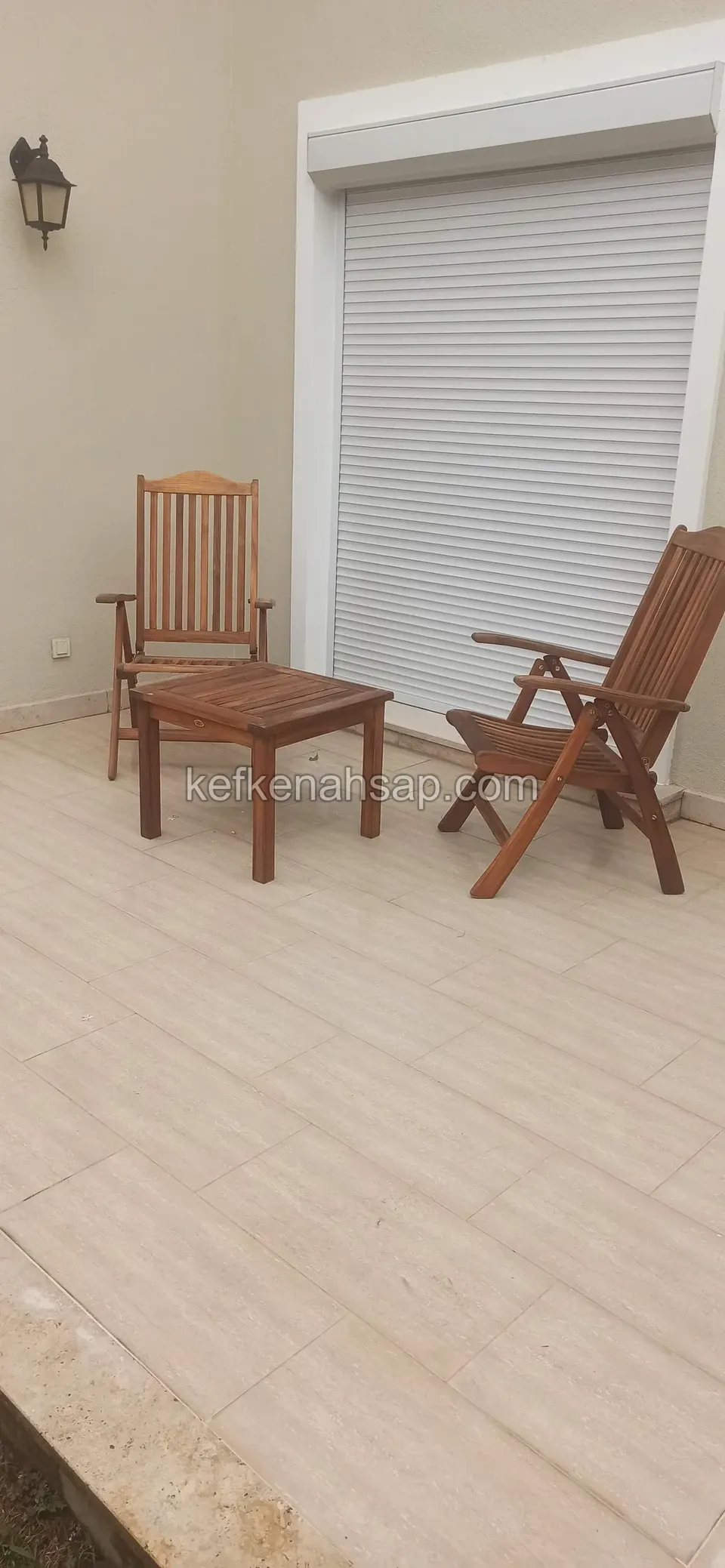 Açık renkli fayans terasta, kapalı beyaz rulo panjurun önünde