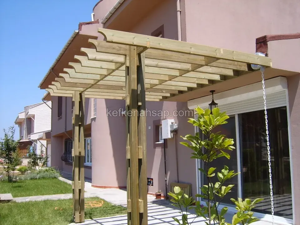 Pembe cepheli villaya bitişik açık renkli ahşap pergola, yan duvarda cam kapı ve bahçede limon ağacı