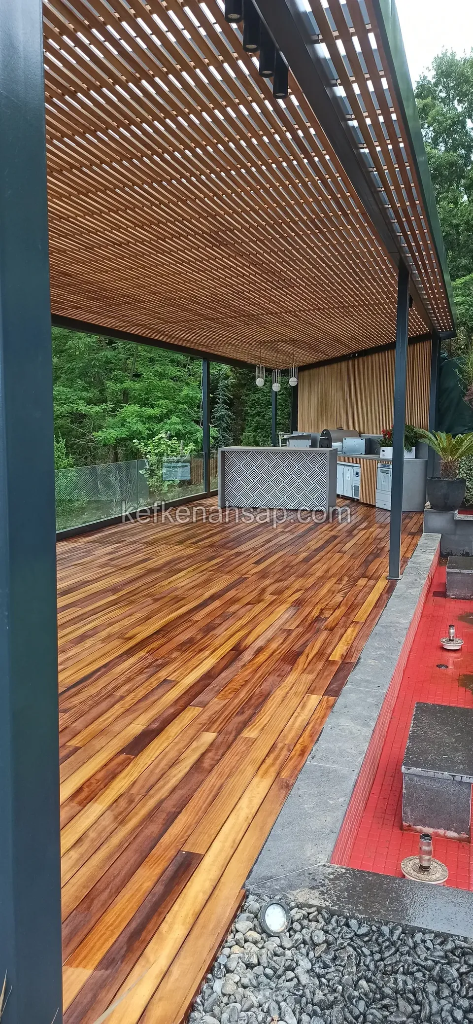 Çıtalı ahşap tavanlı metal pergola altında renk geçişli ahşap deck ve arkada dış mutfak