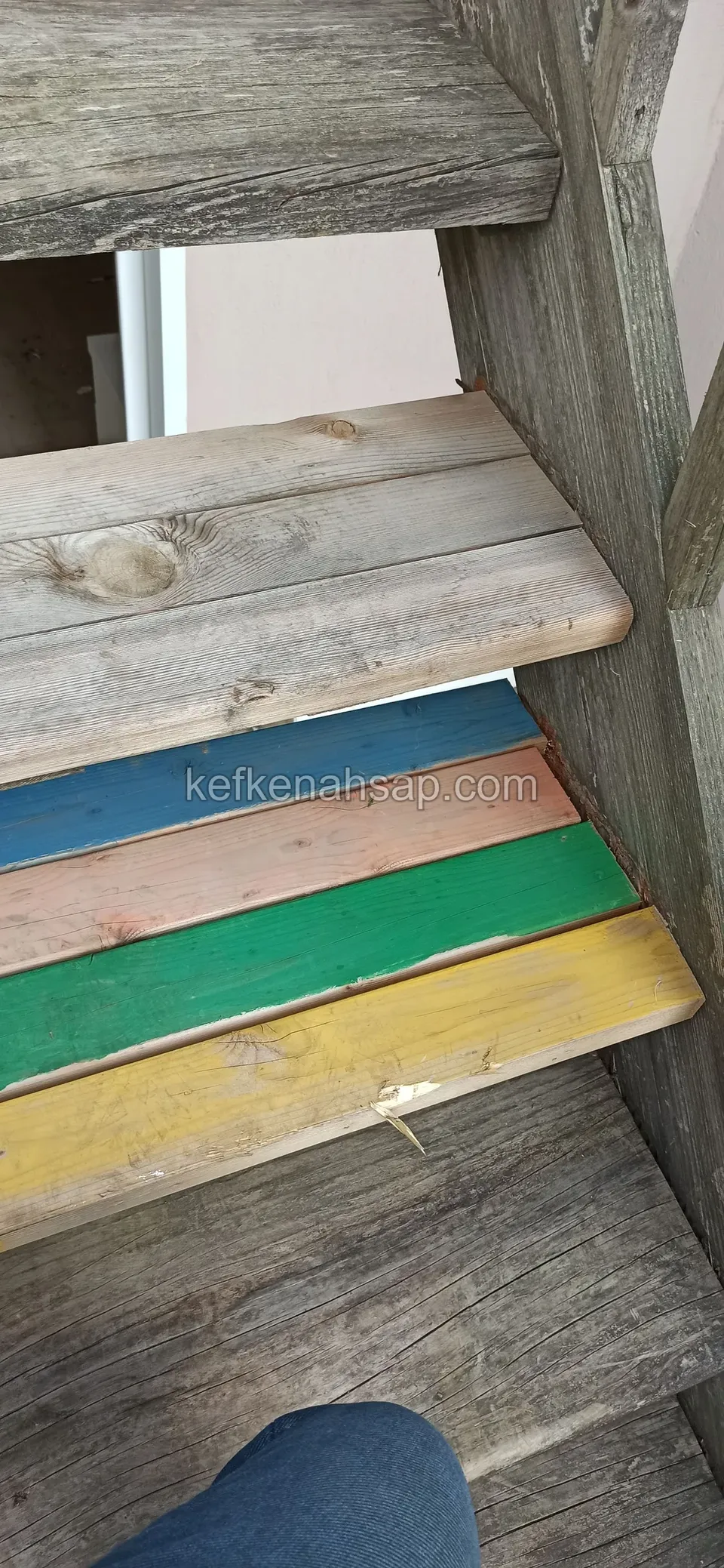 Eski ahşap merdivende mavi, turuncu, yeşil ve sarıya boyanmış basamak yüzleri