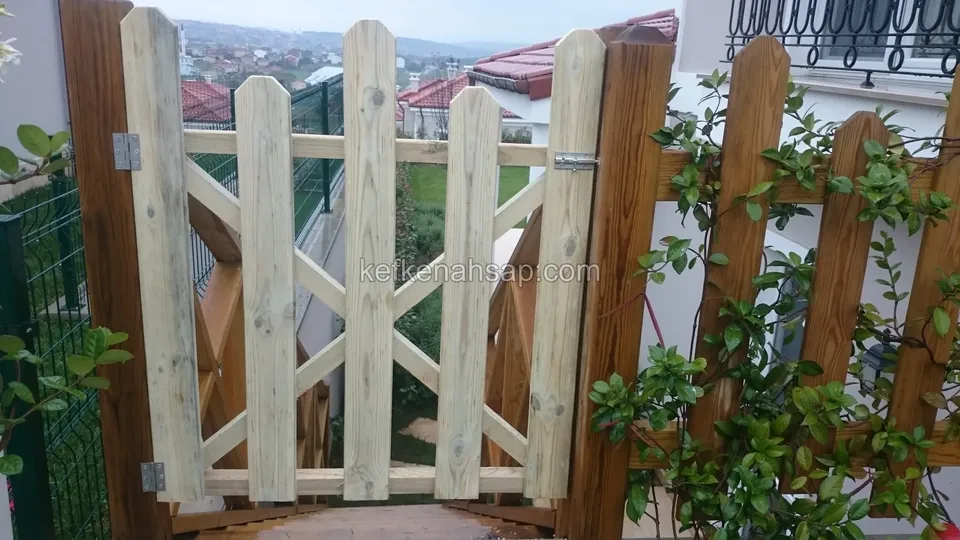 Sarmaşık sarılmış kahverengi tonlu ahşap çitin arasında açık renkli, çapraz destekli ahşap bahçe kapısı