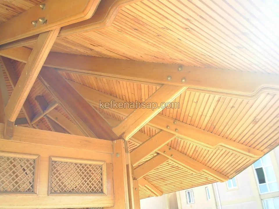 Inside an octagonal gazebo: honey-toned lining-board ceiling, beams and lattice panels below, in warm light
