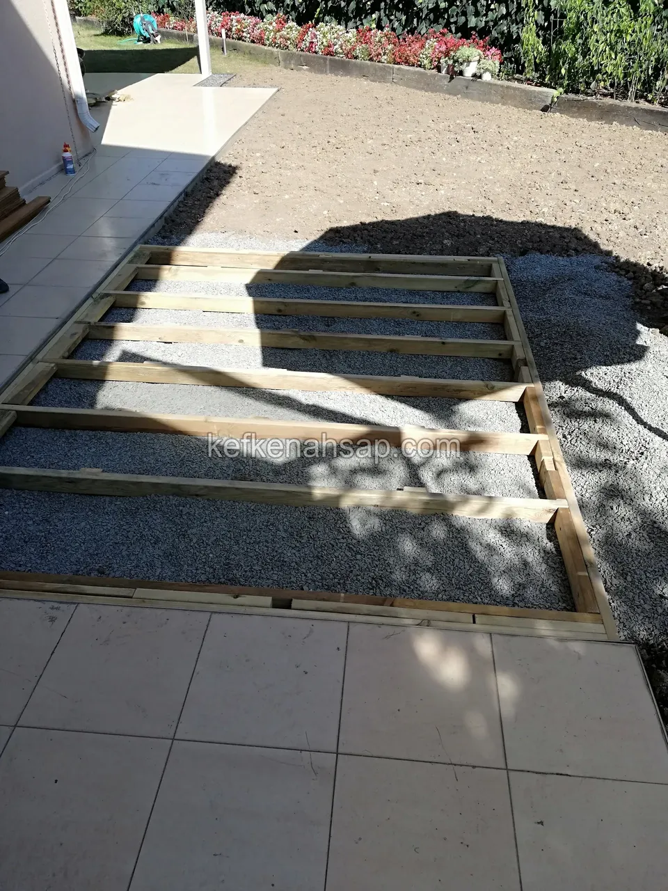 Deck substructure of slim joists on gravel, with ceramic flooring alongside