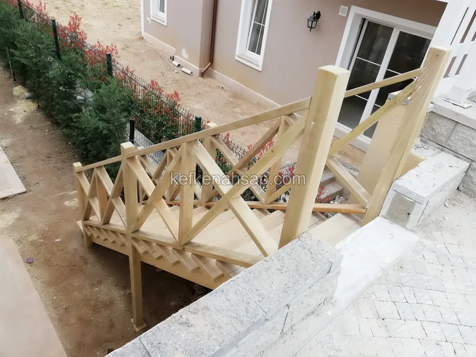 Holztreppe und Podest auf Stützen in einem steingefassten Bereich, mit Kreuzstreben-Geländer