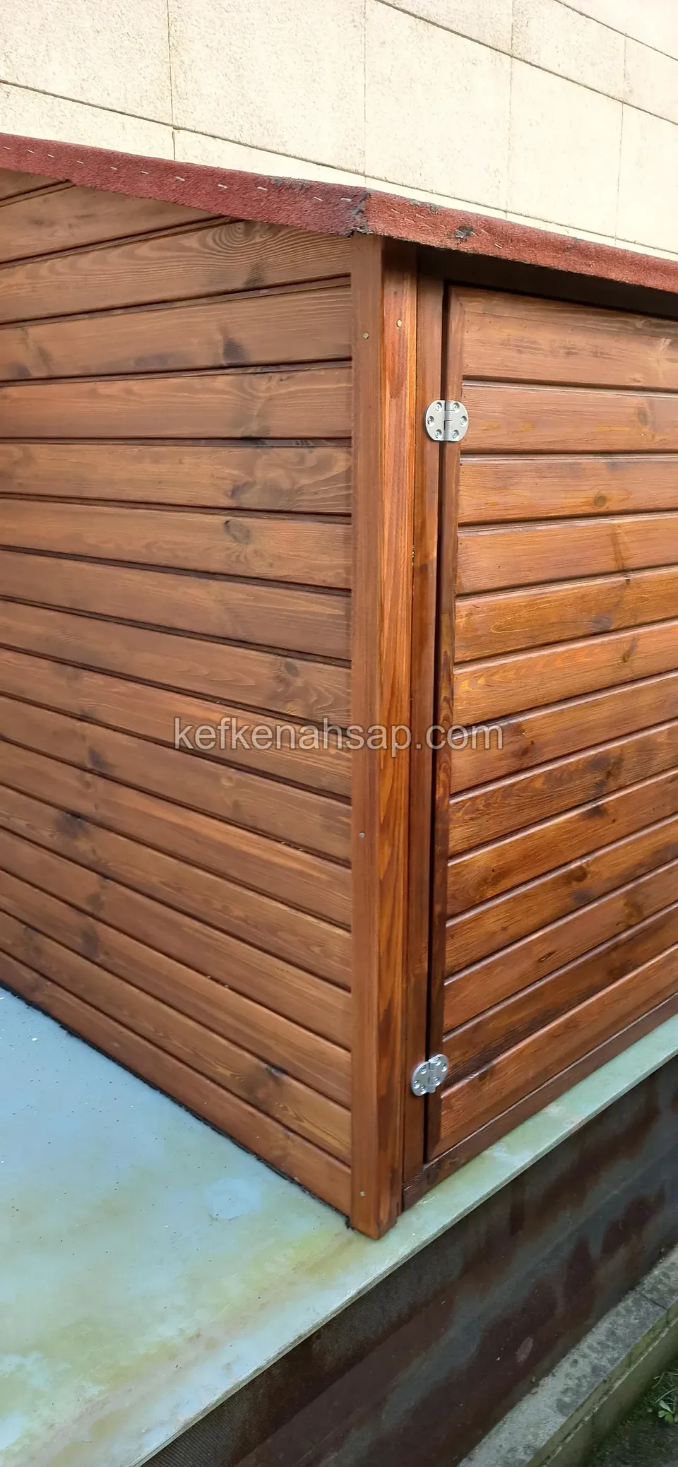 Ecke eines niedrigen Holzschranks am Wandfuß, mit waagerechten Brettern