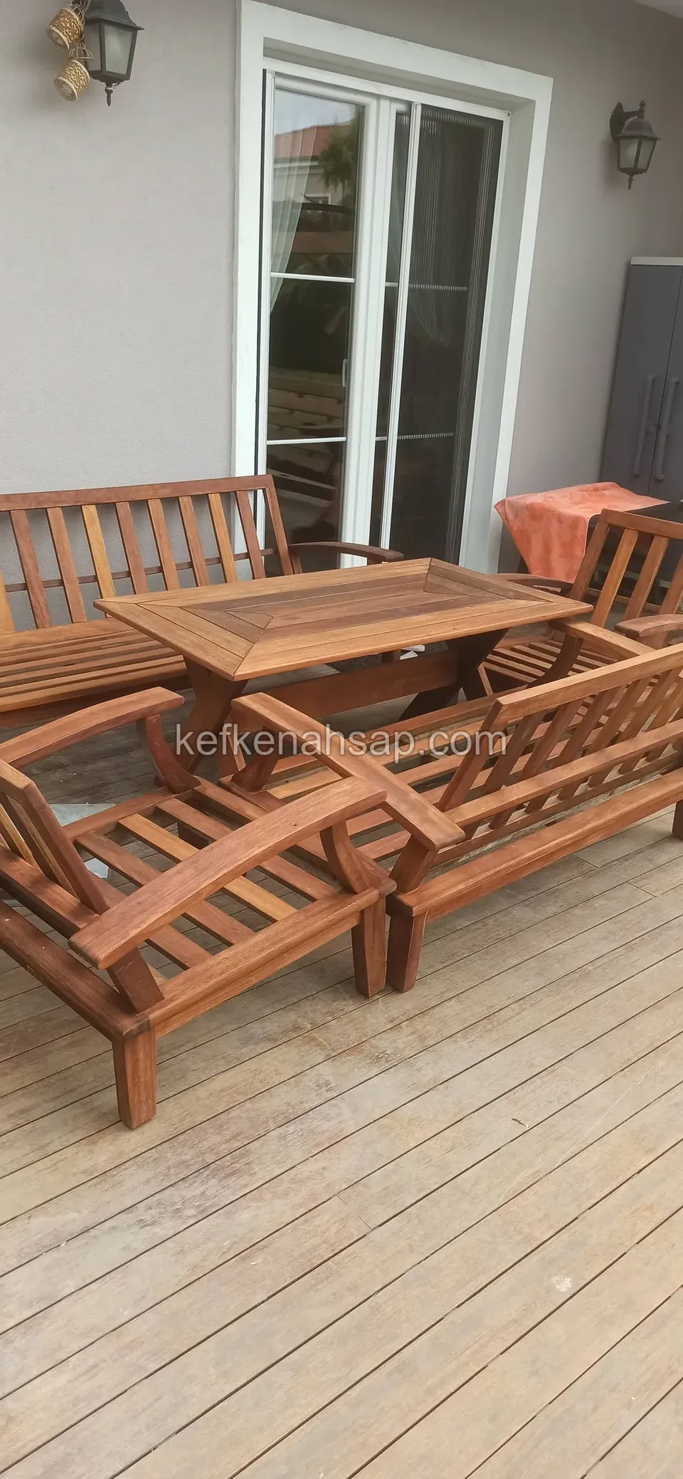 Cam kapılı evin deck terasında ahşap kanepe, koltuklar ve orta masa