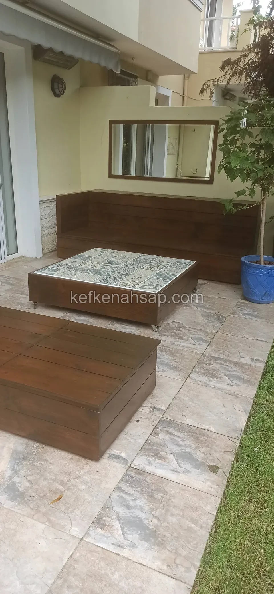 In the corner of a terrace with yellow walls, a dark timber L-shaped seating unit