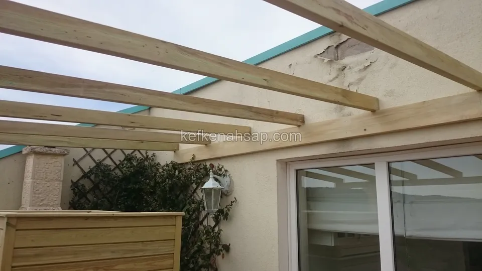 Terasta emprenyeli çam pergola kirişleri, cam sürgülü kapılı duvar, kafes panel ve ahşap saksılık