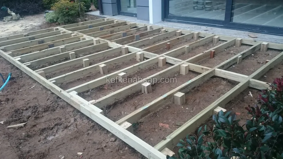 Timber deck joist frame on soil with short blocks between the joists and shrubs alongside