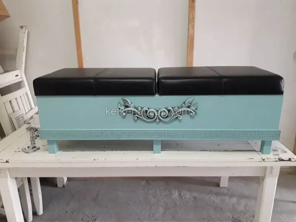 Turquoise painted storage bench with black leather cushions, a carved ornament and a Greek key band on the front