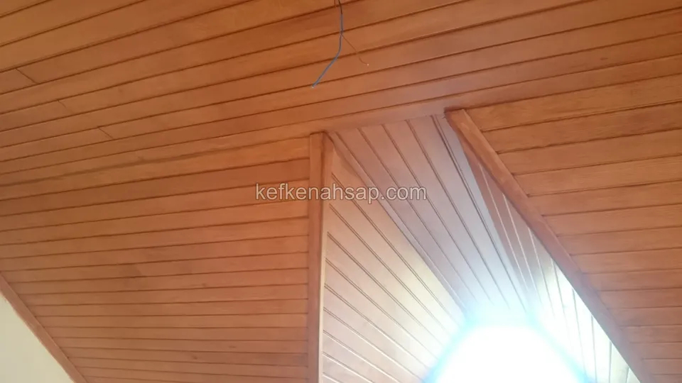 Turuncu tonlu vernikli lambri tavan, ortasında basamak yapan eğimli bölüm ve içeri ışık dolduran parlak bir pencere