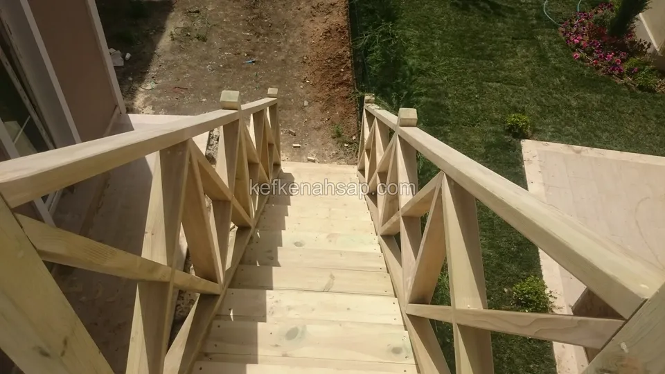 Üstten bakışla düz basamaklar ve iki yanda çaprazlı korkuluk; yanda çimlik ve çiçekler