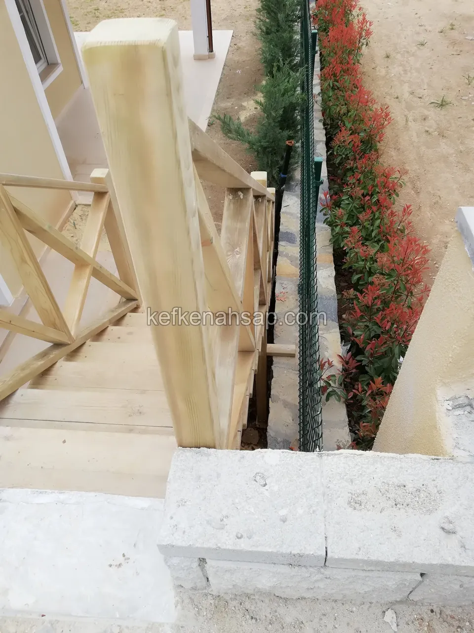 Draufsicht auf eine schmale Holztreppe mit Kreuzstreben-Geländer an kräftigen Pfosten