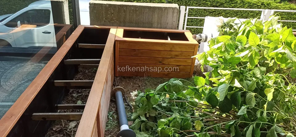 Close view of the cross battens, water pipe and neighbouring green plants inside a long timber planter