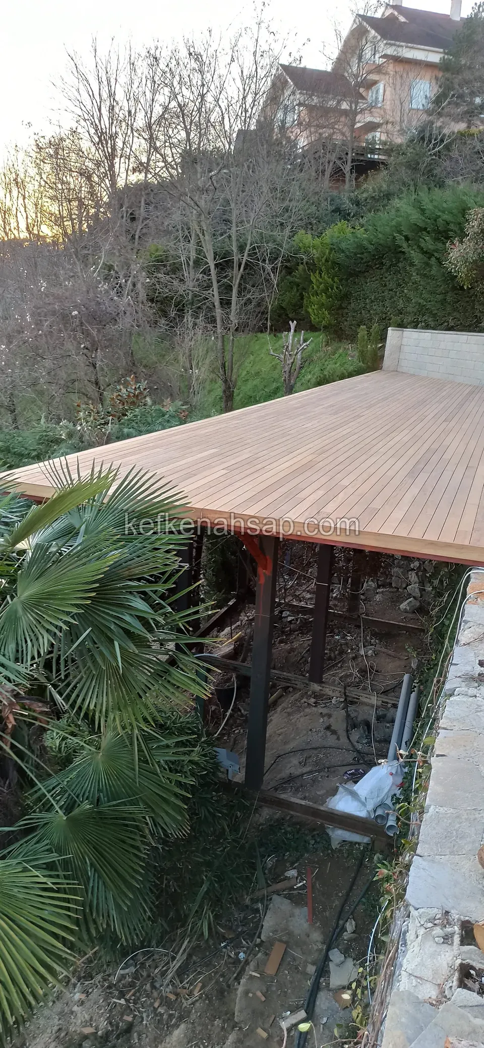 Wide pale timber deck on steel legs, reaching out over a slope