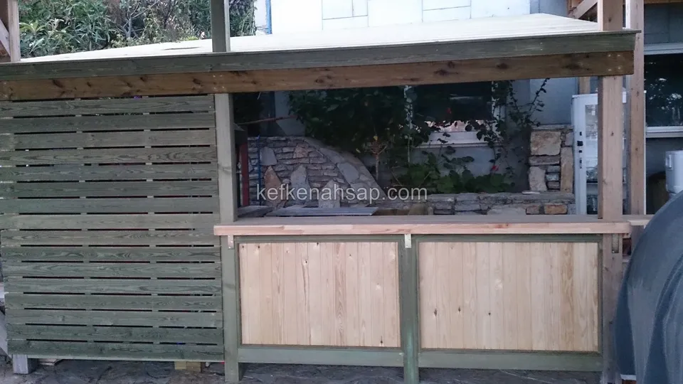 Yatay çıtalı yeşilimsi duvar ve ön yüzü açık renk tahta paneli olan, henüz bitmemiş ahşap bar bölümü