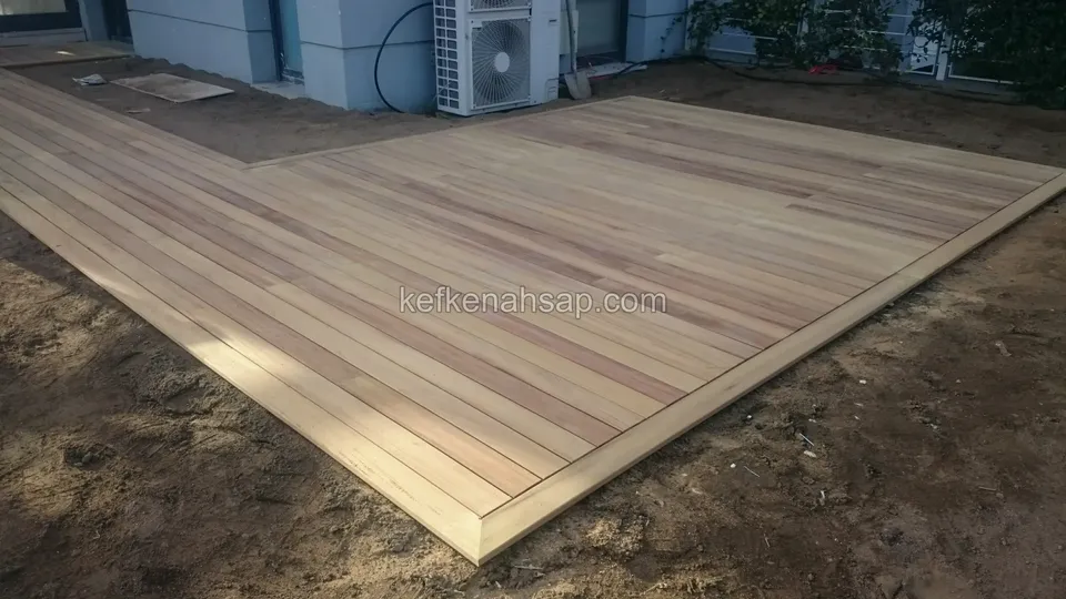 Newly laid timber deck floor with bare soil around it and an AC unit behind