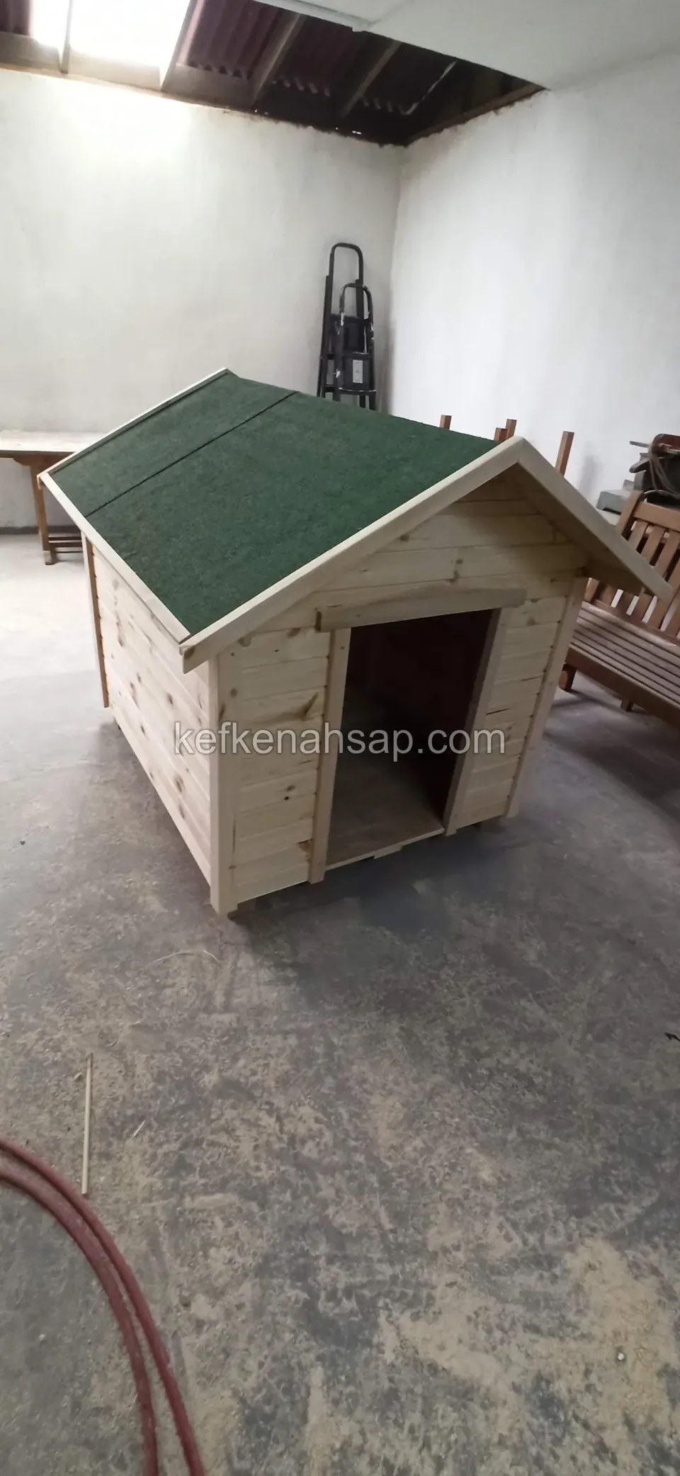 Yeşil shingle çatılı, doğal tonlu köpek kulübesi, atölye zemininde ön cepheden